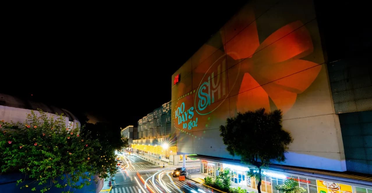 An SM mall facade at night with a 100 days to go Christmas projection
