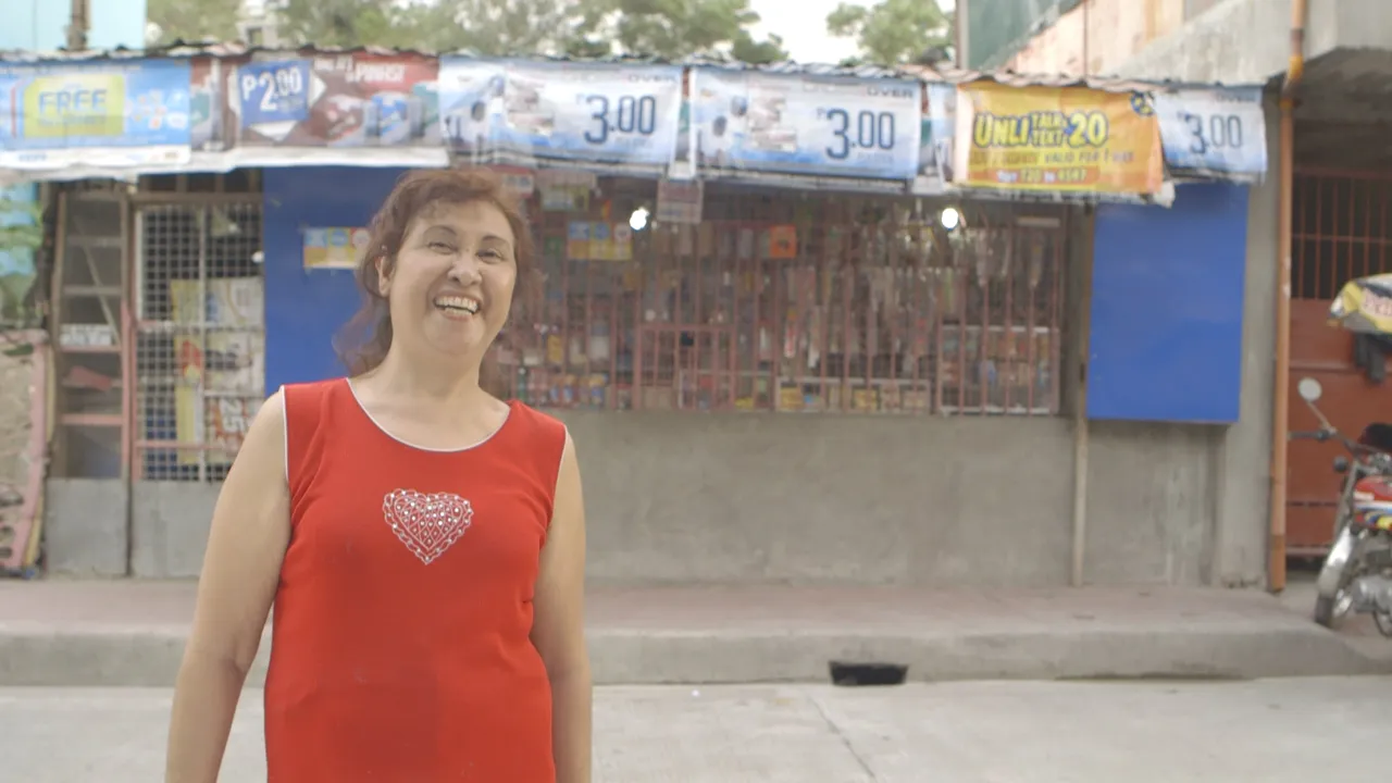 A sari-sari store owner standing in front of her shop